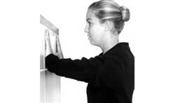 Woman performing wall press physical therapy exercise